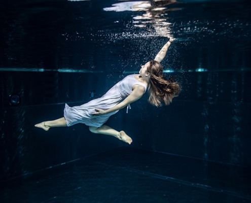 Mädchen im weißen Kleid unter Wasser