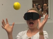Schülerin testet ihr Reaktionsvermögen mit dunkler Brille und Tennisball